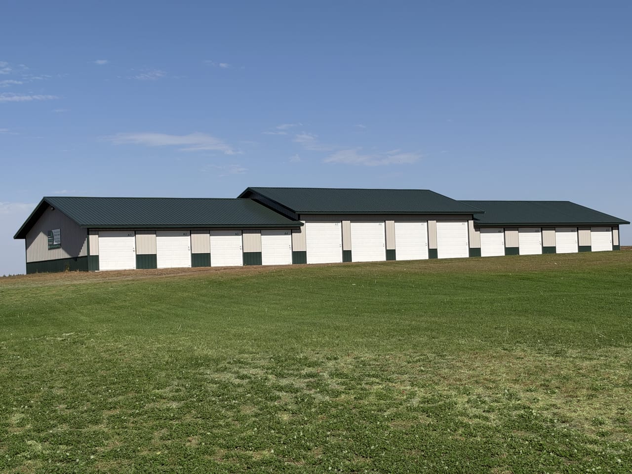 The North Pine Storage building on a sunny day, a long row of white overhead doors behind a green lawn