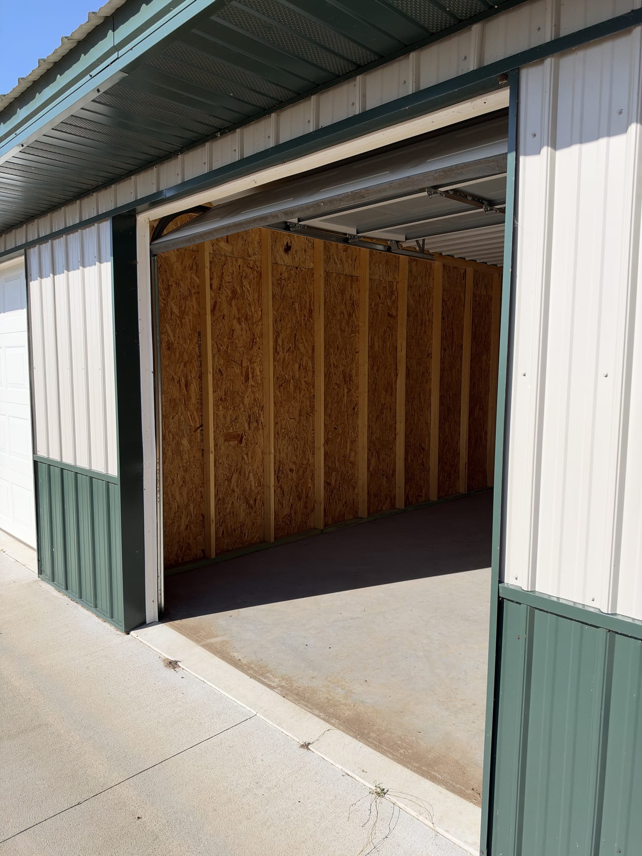 A midsize unit with its 8 x 8 overhead door open, plywood-lined walls and a concrete floor
